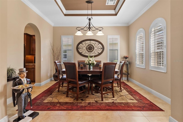 dining space with ornamental molding, a tray ceiling, and an inviting chandelier