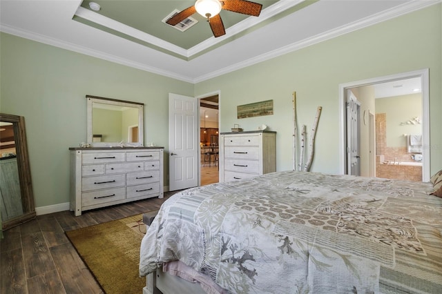 bedroom featuring dark wood-type flooring, a tray ceiling, ensuite bath, ornamental molding, and ceiling fan