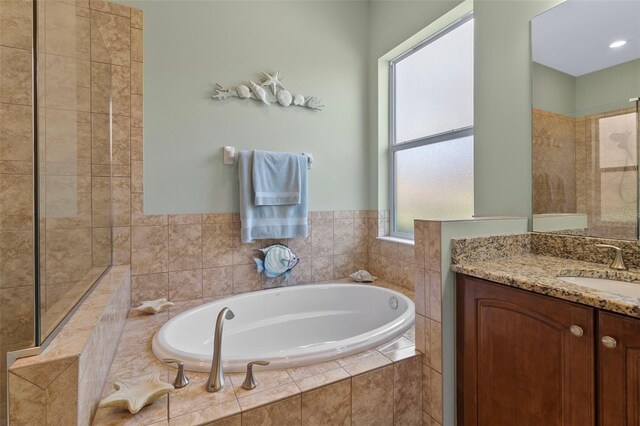 bathroom featuring vanity, tiled bath, and a healthy amount of sunlight