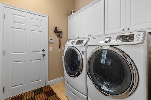 laundry room featuring light tile patterned flooring, washing machine and dryer, and cabinets