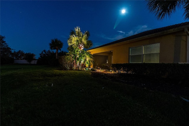 property exterior at night featuring a yard