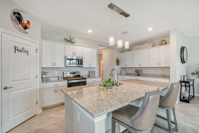 kitchen with appliances with stainless steel finishes, white cabinetry, and a kitchen island with sink