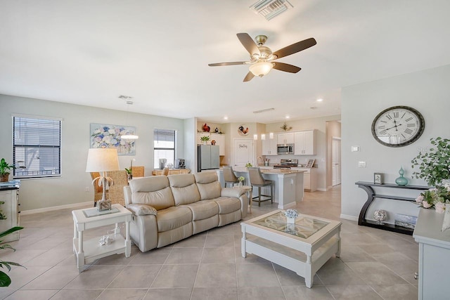 tiled living room featuring ceiling fan and plenty of natural light