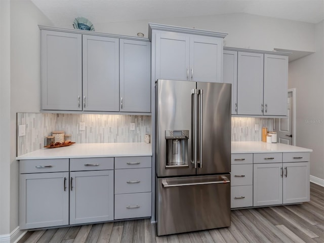 kitchen featuring tasteful backsplash, high end fridge, light hardwood / wood-style flooring, gray cabinets, and vaulted ceiling