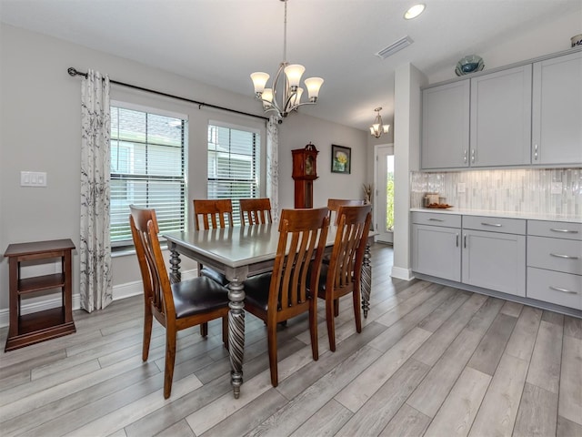 dining space featuring an inviting chandelier, light wood-type flooring, and a healthy amount of sunlight