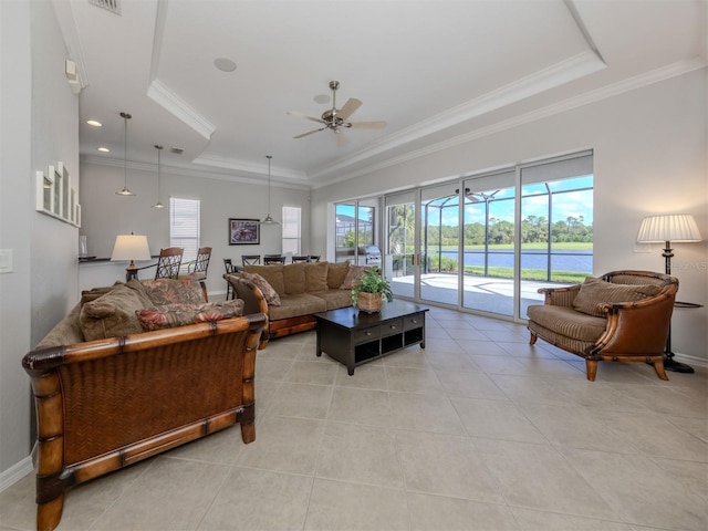 tiled living room with ceiling fan, a tray ceiling, and ornamental molding