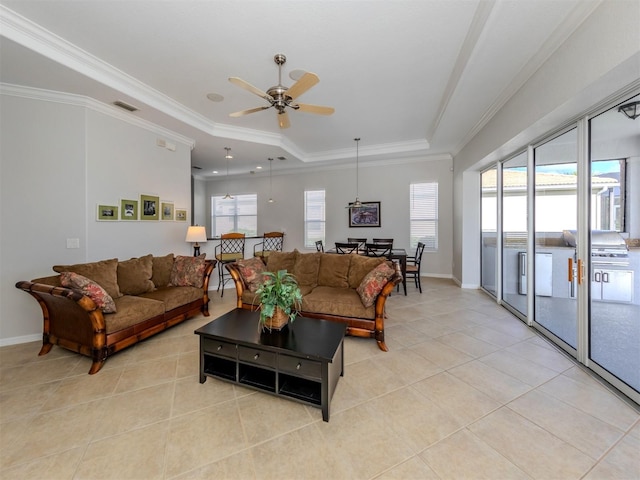 tiled living room featuring a raised ceiling, ornamental molding, and ceiling fan