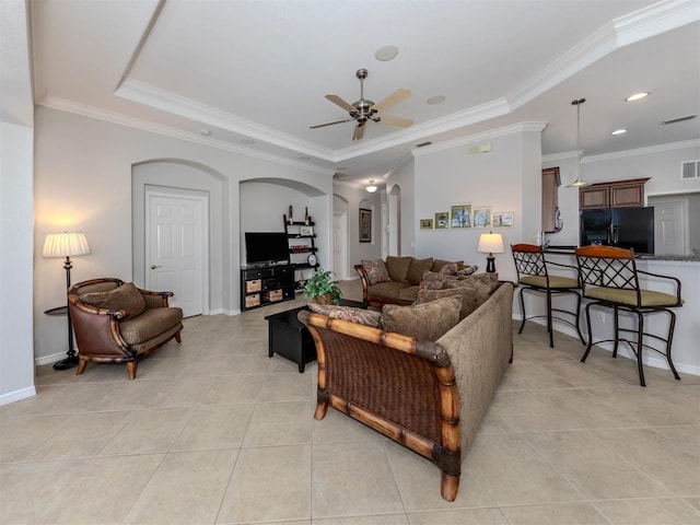 living room featuring ornamental molding, ceiling fan, a tray ceiling, and light tile patterned floors