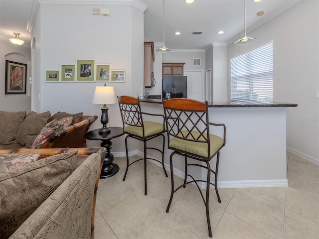 kitchen with pendant lighting, black refrigerator with ice dispenser, ornamental molding, and kitchen peninsula