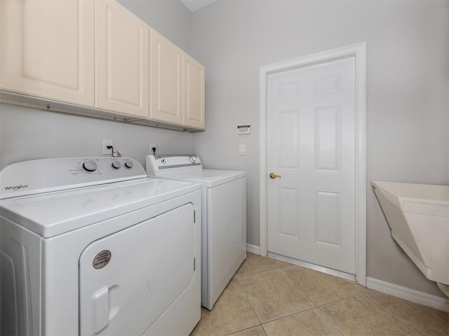 laundry room with cabinets, light tile patterned floors, and washing machine and dryer