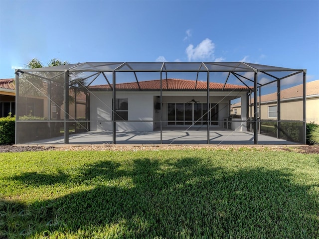 back of house with ceiling fan, a lawn, a lanai, and a patio area