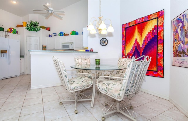 dining room with light tile patterned flooring, ceiling fan with notable chandelier, and high vaulted ceiling