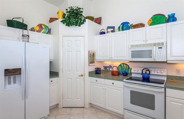 kitchen featuring white appliances, white cabinetry, dark countertops, and light tile patterned floors