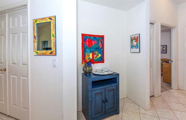 hall featuring baseboards and light tile patterned floors