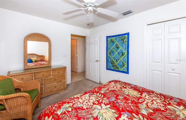 bedroom with visible vents, a ceiling fan, a closet, and light colored carpet