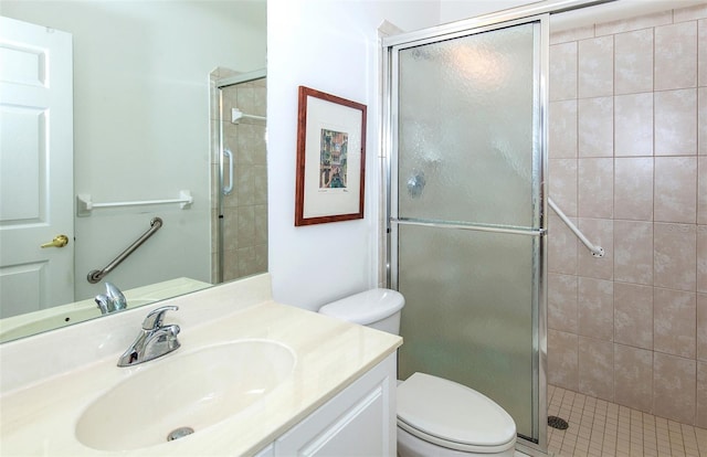 bathroom featuring tile patterned flooring, a shower with shower door, vanity, and toilet