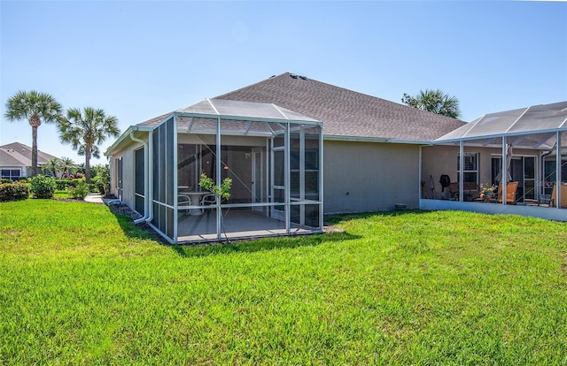rear view of house featuring a lawn, glass enclosure, and a patio