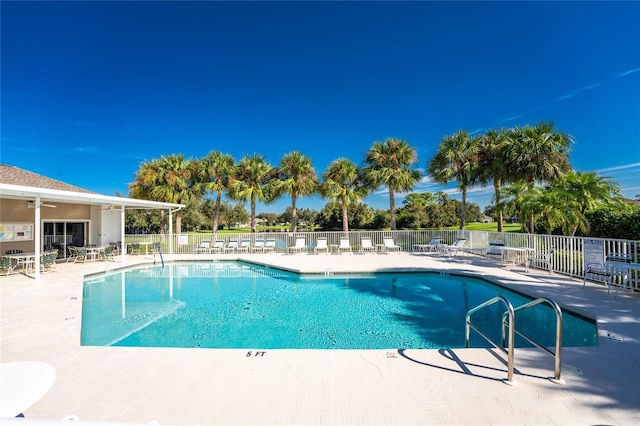 community pool featuring fence, a ceiling fan, and a patio area