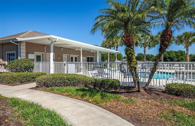 view of front of house featuring a community pool, fence, and stucco siding