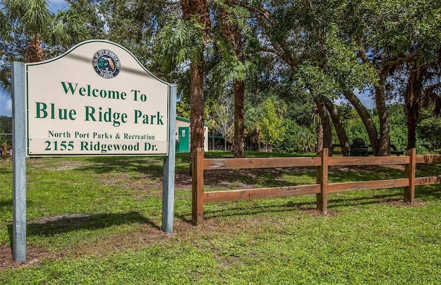 community sign featuring a lawn and fence