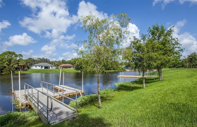 view of dock with a lawn and a water view