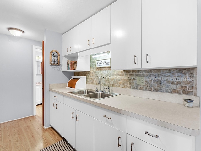 kitchen featuring white cabinetry, sink, light hardwood / wood-style floors, and decorative backsplash