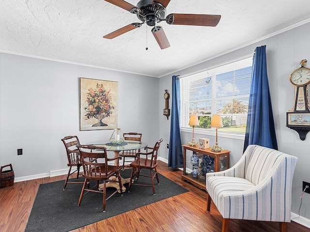 dining space featuring ceiling fan, wood-type flooring, ornamental molding, and a textured ceiling