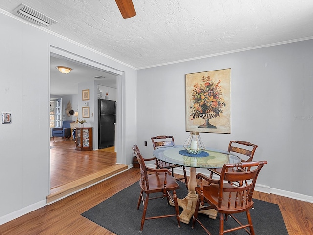 dining area with crown molding, hardwood / wood-style flooring, and a textured ceiling