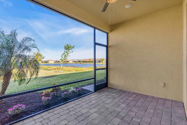 unfurnished sunroom with ceiling fan and a water view