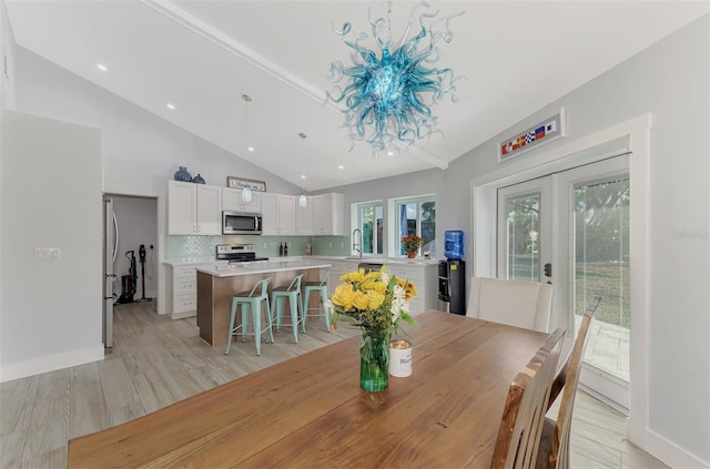 dining area with lofted ceiling, sink, and light hardwood / wood-style flooring