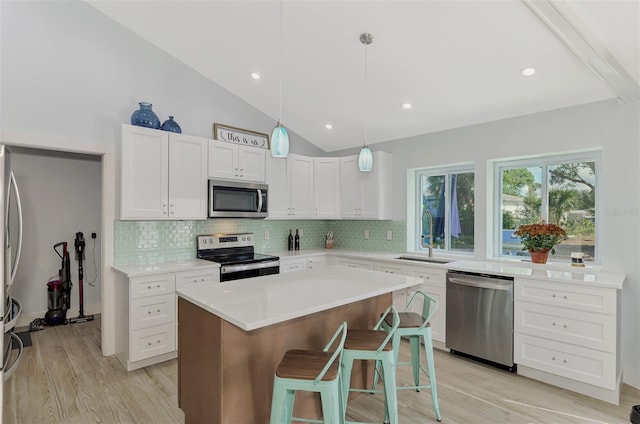 kitchen with appliances with stainless steel finishes, light wood-type flooring, a kitchen breakfast bar, sink, and a center island