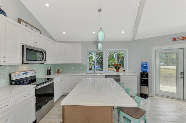 kitchen featuring white cabinets, vaulted ceiling with beams, stainless steel appliances, and a kitchen island