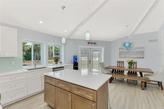 kitchen with white cabinetry, sink, light hardwood / wood-style floors, and decorative light fixtures