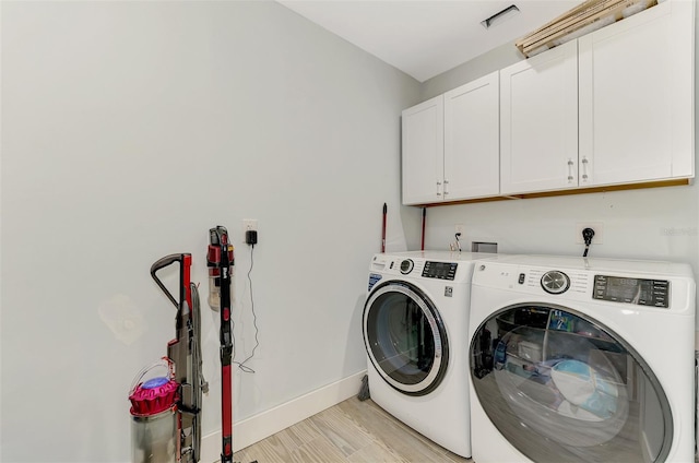 laundry area featuring cabinets, light wood-type flooring, and independent washer and dryer