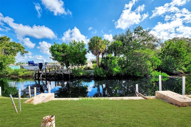 view of dock featuring a lawn and a water view