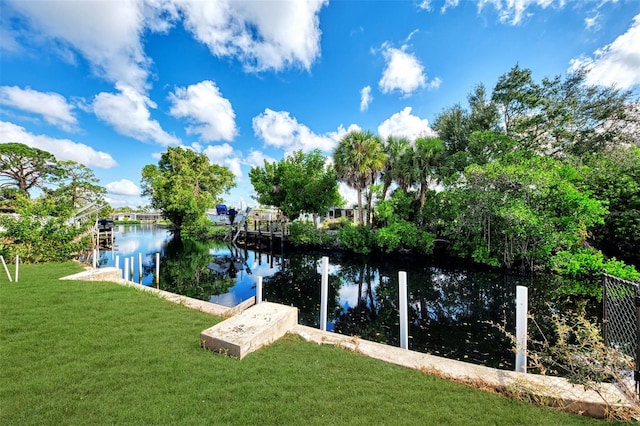 view of dock with a lawn and a water view