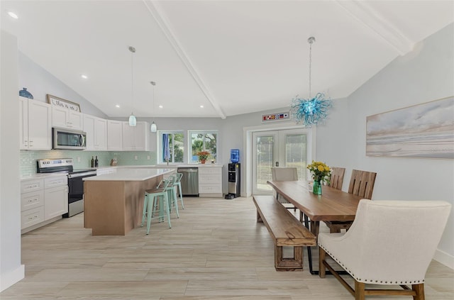 kitchen with white cabinetry, a center island, hanging light fixtures, stainless steel appliances, and lofted ceiling with beams