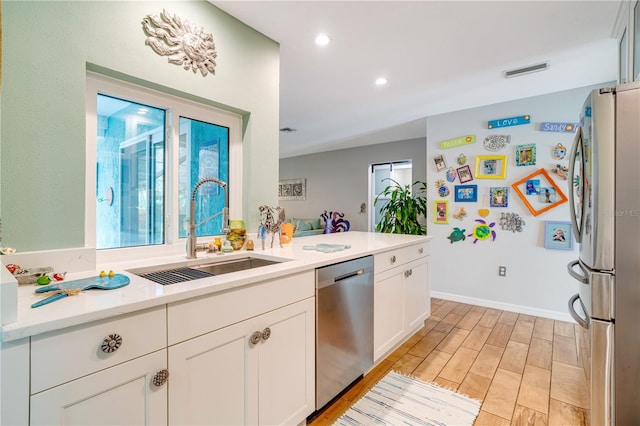 kitchen featuring white cabinetry, stainless steel appliances, sink, and light wood-type flooring