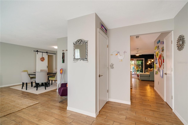 hallway featuring light hardwood / wood-style floors and a barn door