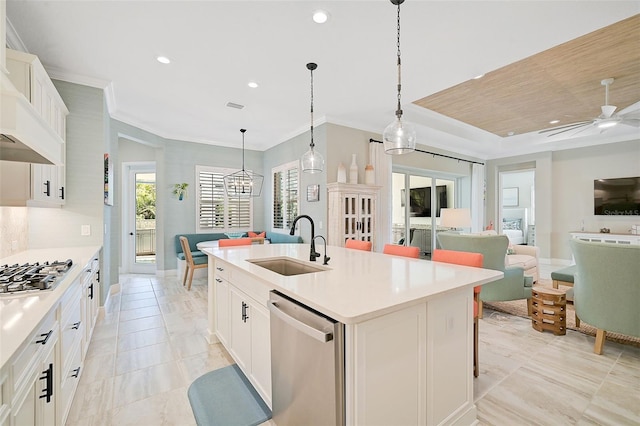 kitchen featuring stainless steel appliances, sink, decorative light fixtures, a kitchen island with sink, and white cabinets