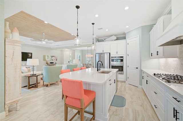 kitchen featuring tasteful backsplash, white cabinets, a center island with sink, and stainless steel appliances