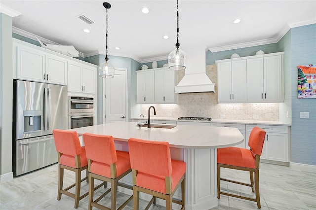 kitchen featuring a center island with sink, sink, custom range hood, white cabinetry, and appliances with stainless steel finishes