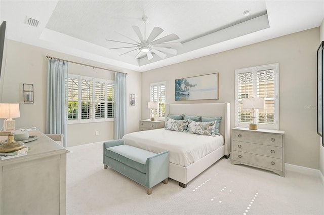 carpeted bedroom featuring a tray ceiling and ceiling fan