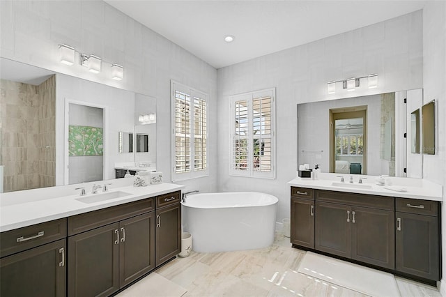 bathroom featuring vanity, a healthy amount of sunlight, a bathing tub, and tile walls