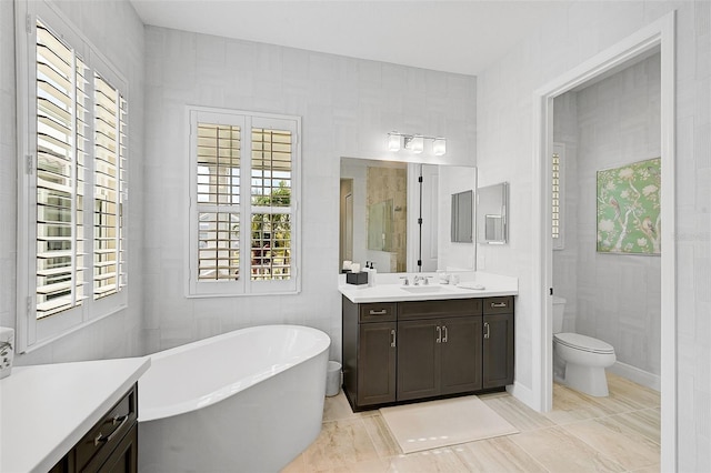 bathroom with vanity, tile patterned floors, toilet, a bathtub, and tile walls