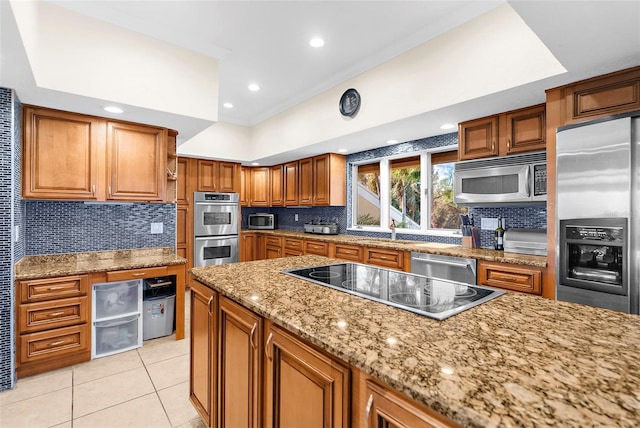 kitchen featuring light stone counters, tasteful backsplash, and appliances with stainless steel finishes