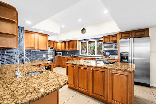 kitchen featuring sink, backsplash, a center island, stainless steel appliances, and light stone counters