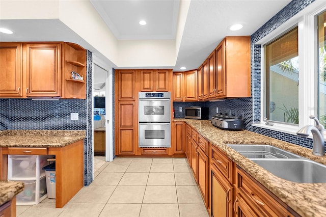 kitchen with decorative backsplash, brown cabinets, stainless steel appliances, and a sink