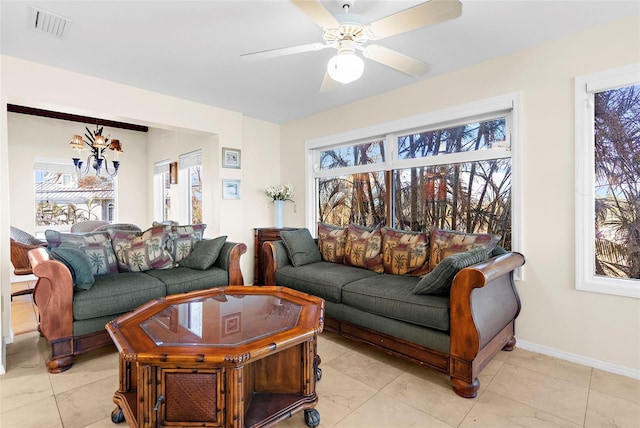 living area with baseboards, a healthy amount of sunlight, visible vents, and ceiling fan with notable chandelier