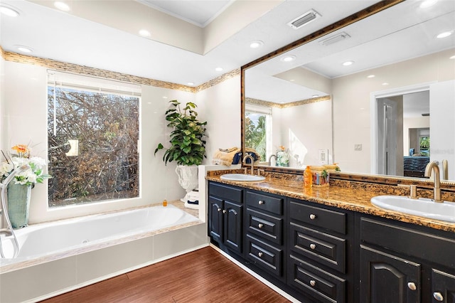 bathroom with vanity, hardwood / wood-style floors, ornamental molding, and a tub